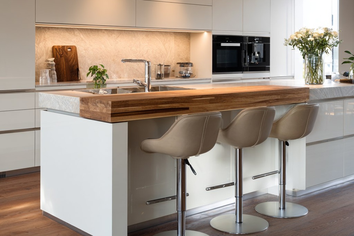 Das Interieur einer hellen Küche mit Halbinsel, das eine Kombination aus natürlichen Materialien zeigt: Holz, Stein und verchromte Details.